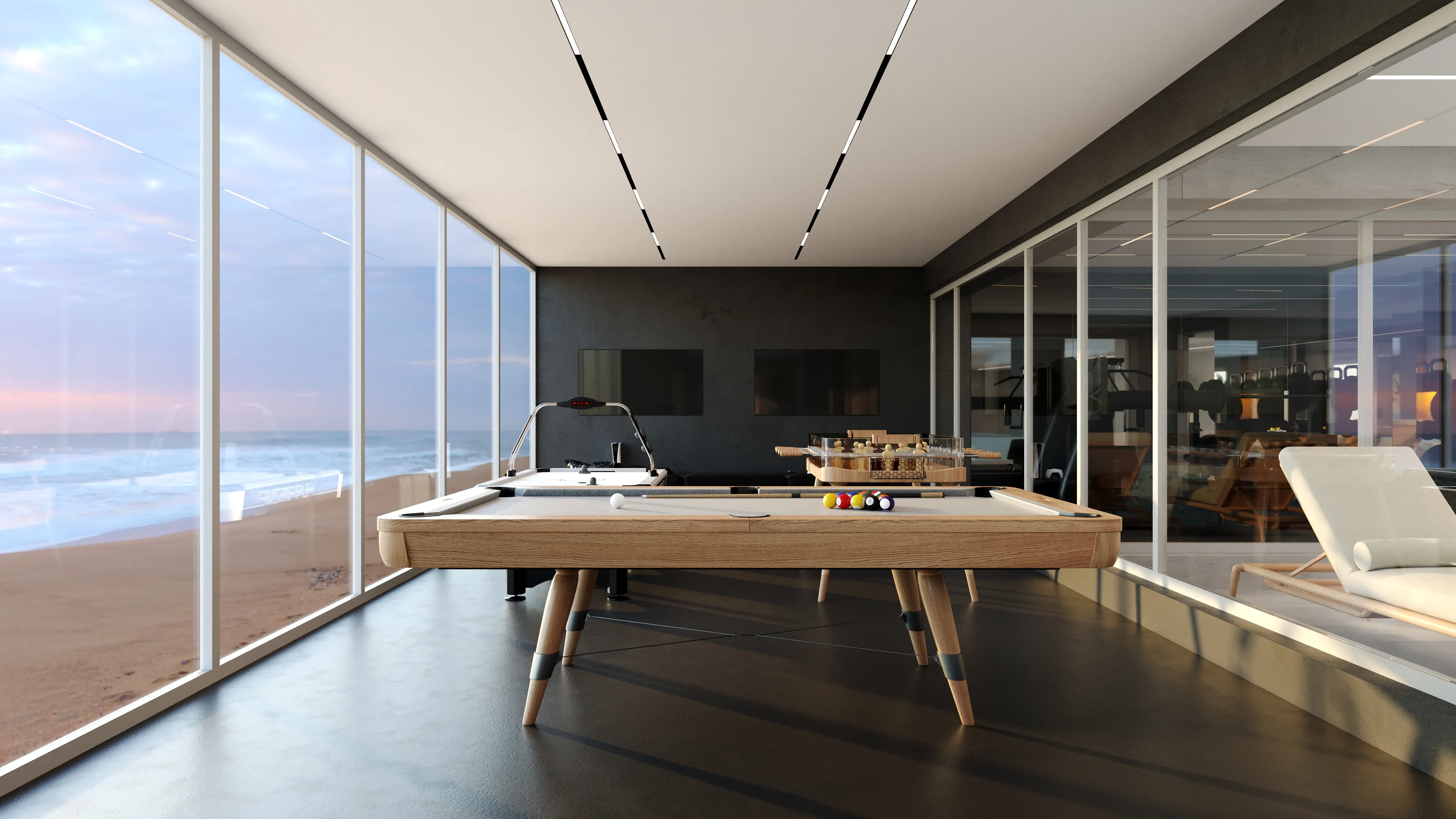 Billiards table beside a wall of glass looking onto the beach at dusk