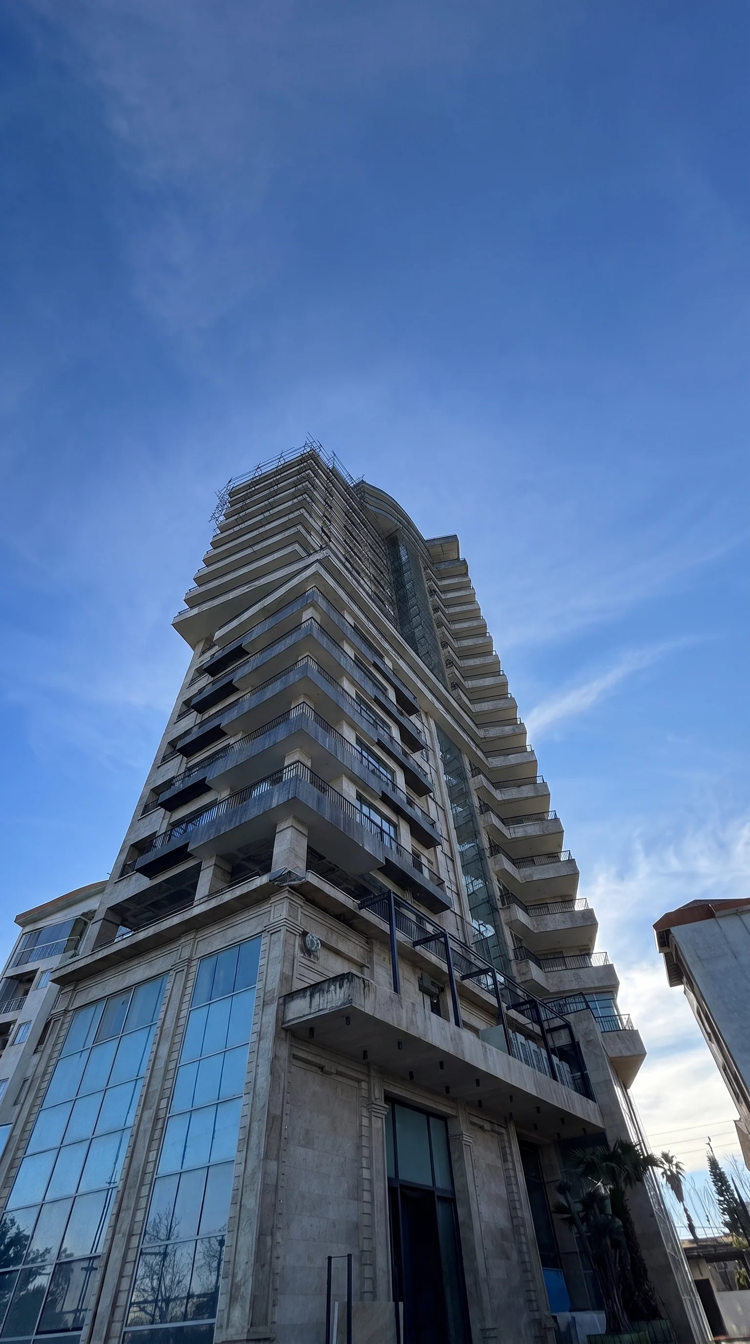 The tower seen from the street, balconies rising above the travertine base