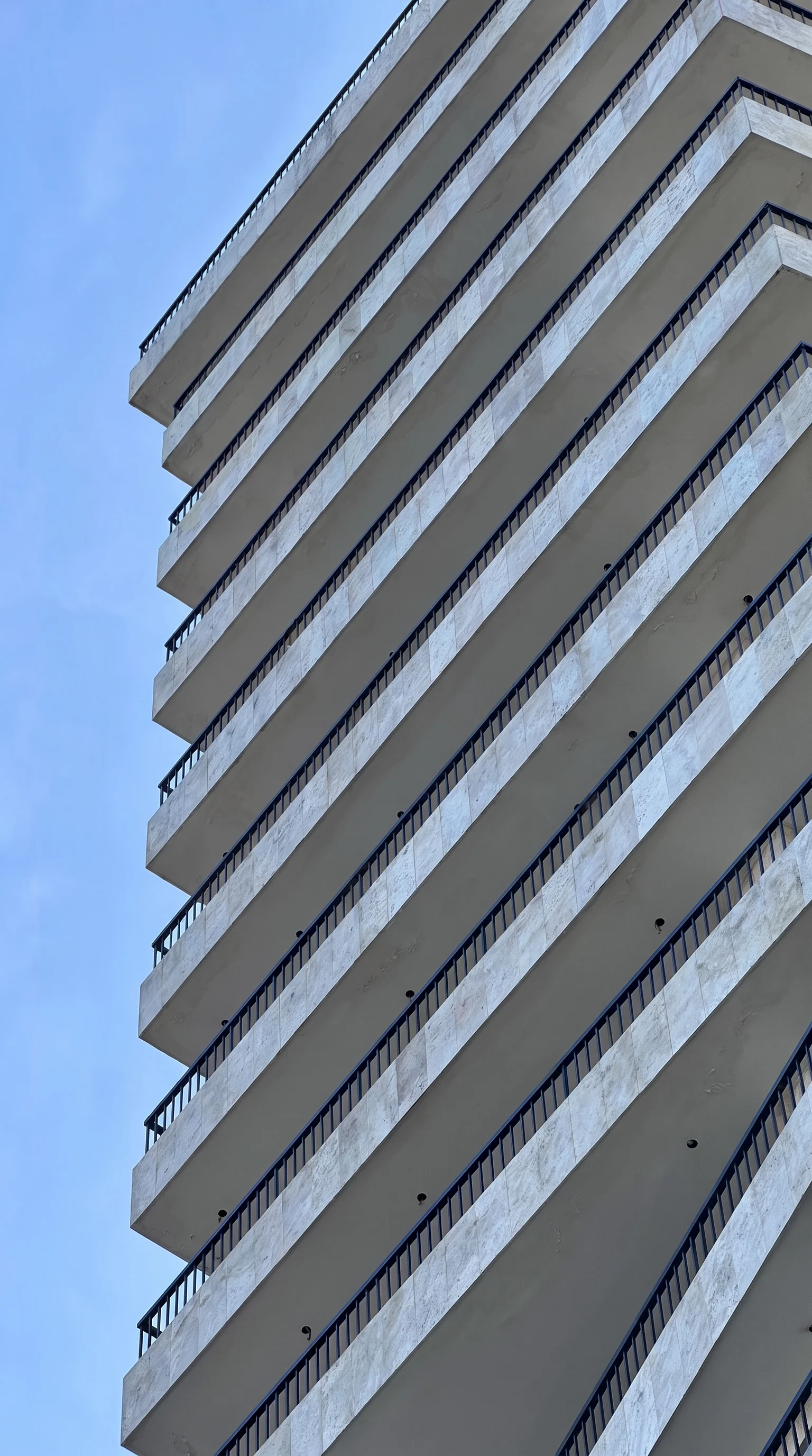 Travertine-clad balconies stacking away against a clear sky
