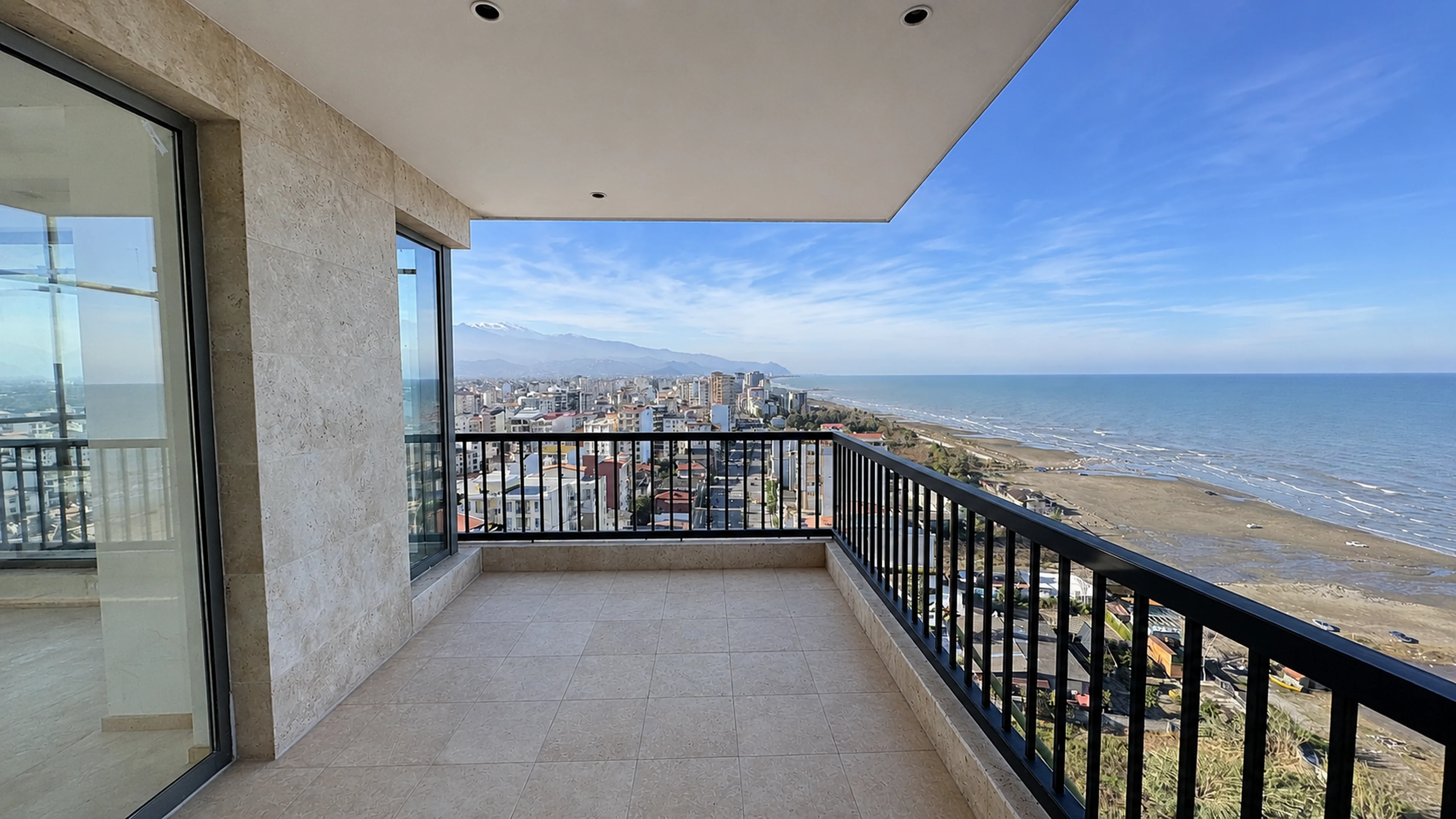 Covered balcony faced in travertine, looking out over the beach to the mountains